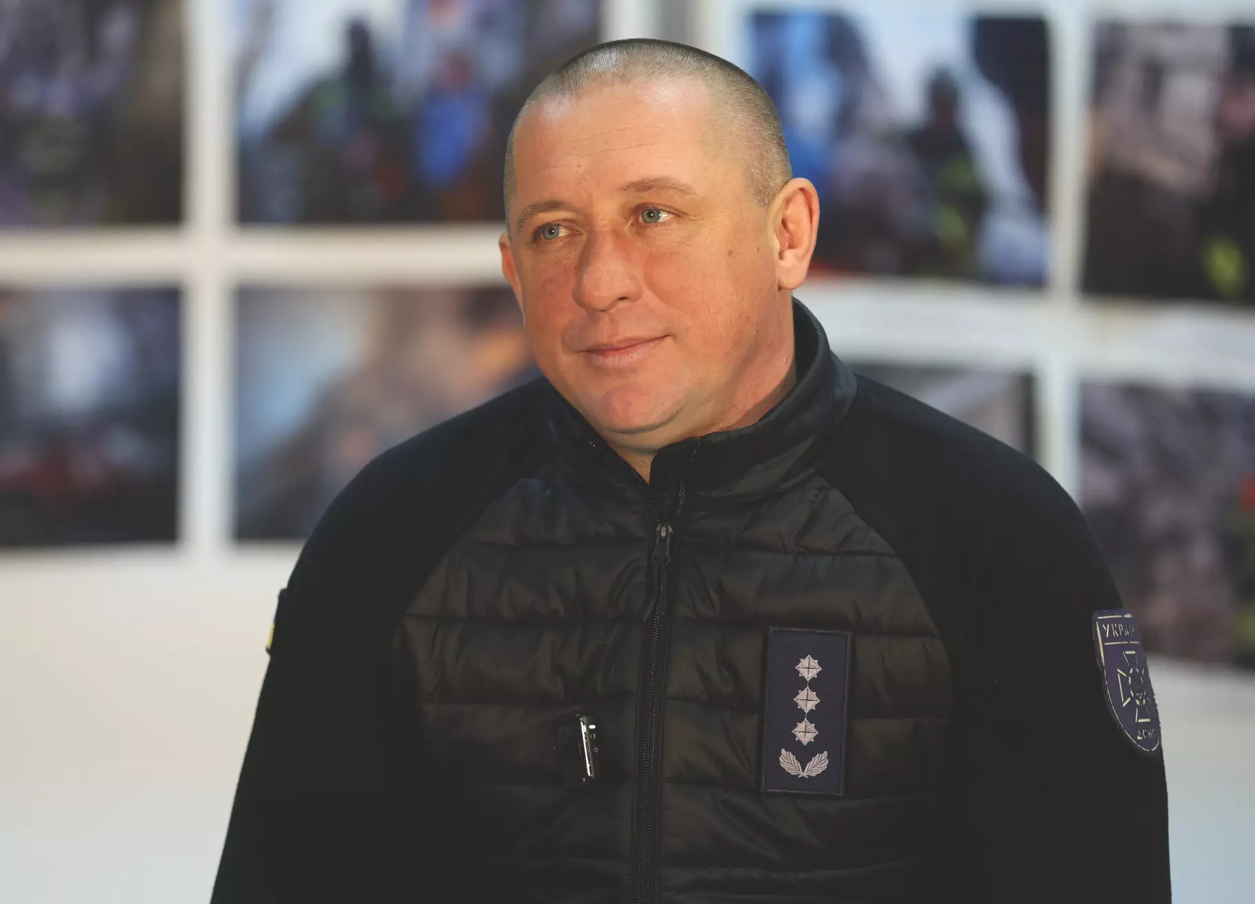 Чоловік у формі ДСНС України на фоні фотографій, пов'язаних з рятувальними операціями
