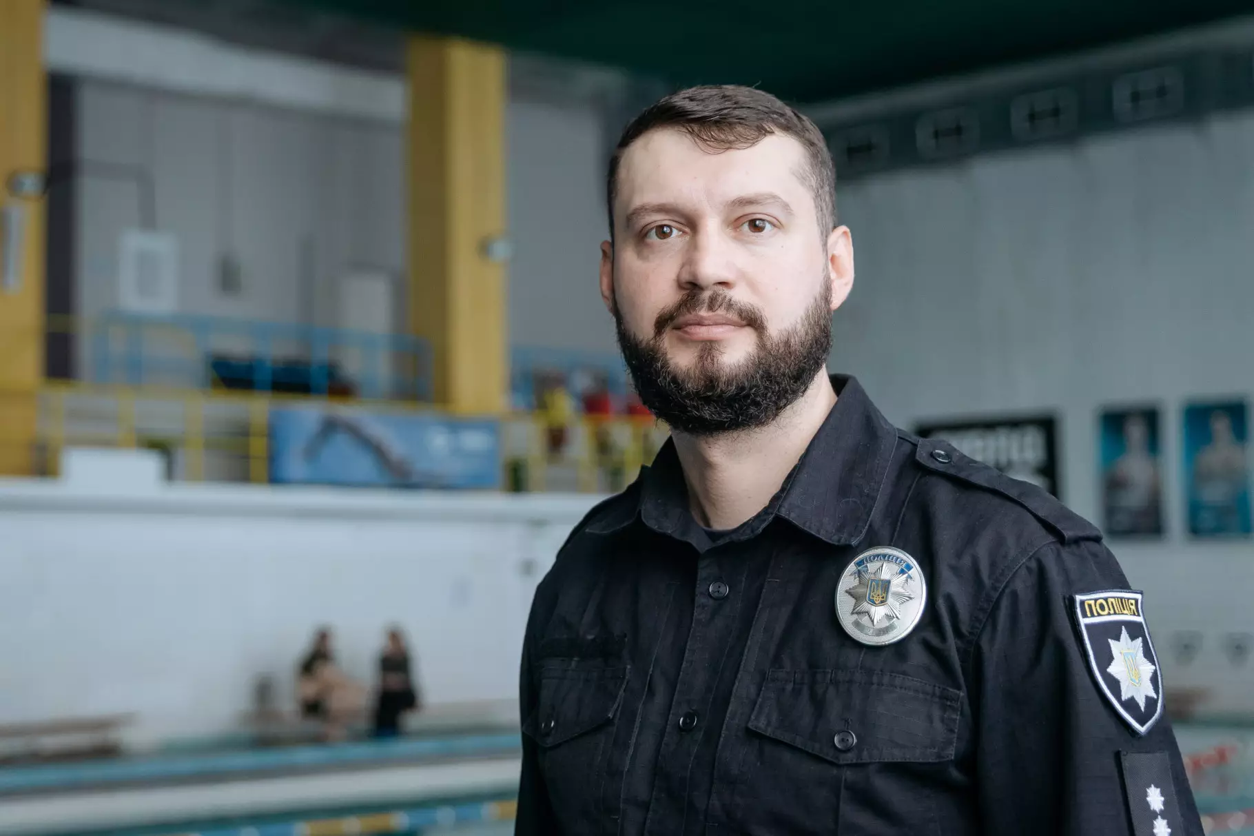 Чоловік у поліцейській формі стоїть біля басейну, де проводяться заняття з дайвінгу для ветеранів