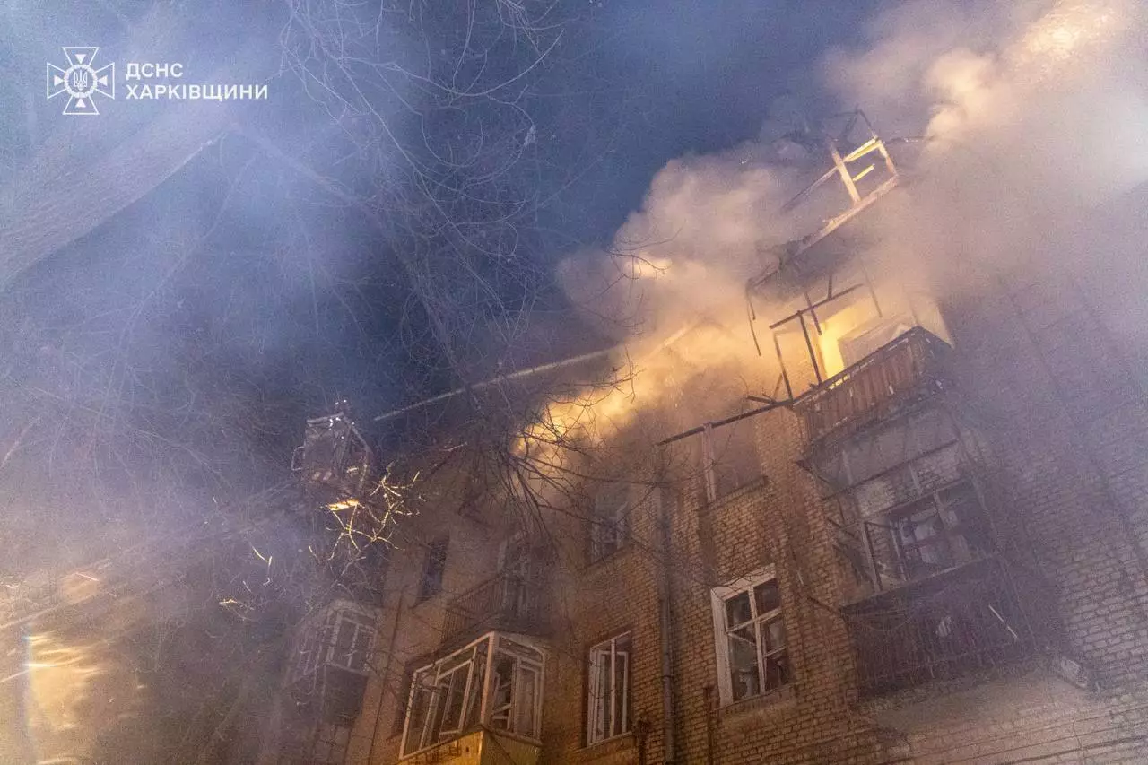 Палаюча багатоповерхівка вночі після російського обстрілу, дим піднімається вгору, рятувальники працюють