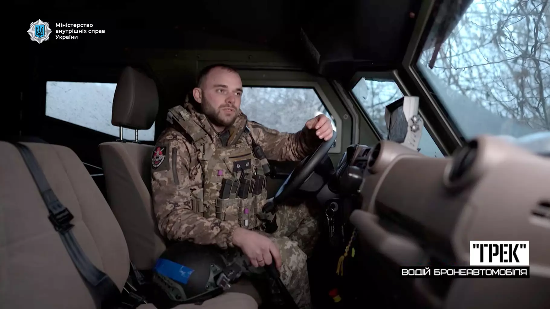 Військовий у камуфляжі сидить за кермом броньованого автомобіля в сірій зоні під час евакуації