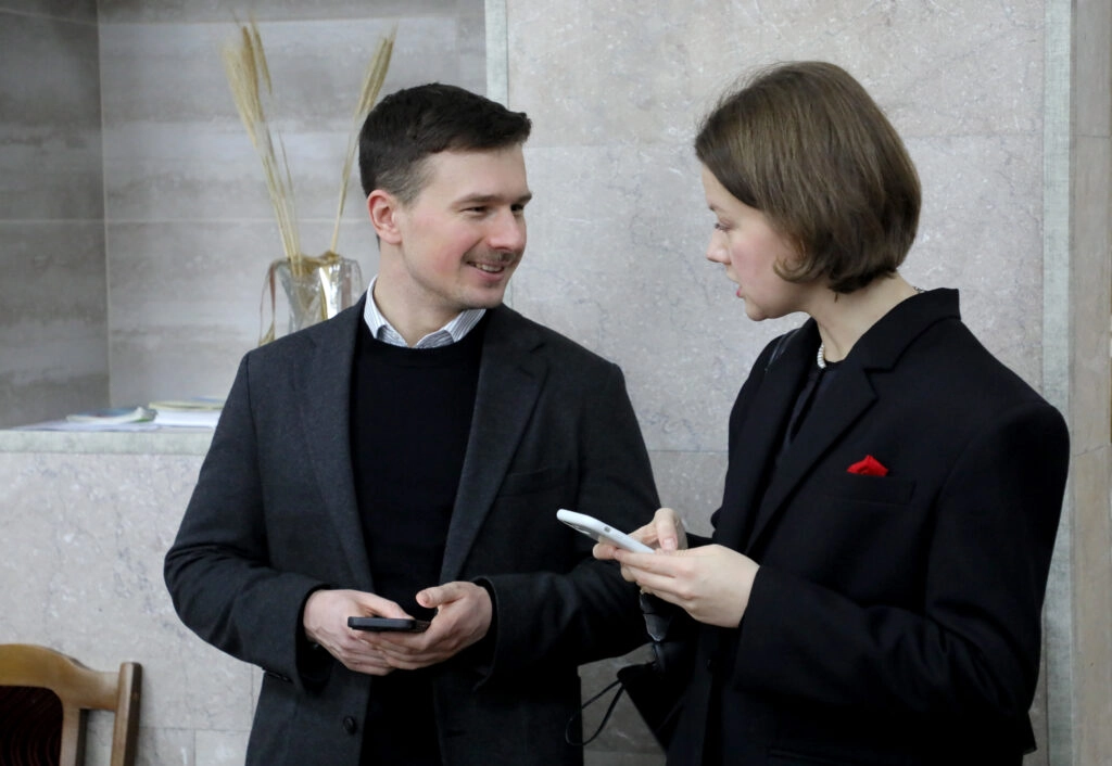 Двоє людей обговорюють питання, тримаючи смартфони, на зустрічі з питань реформ у сфері культури