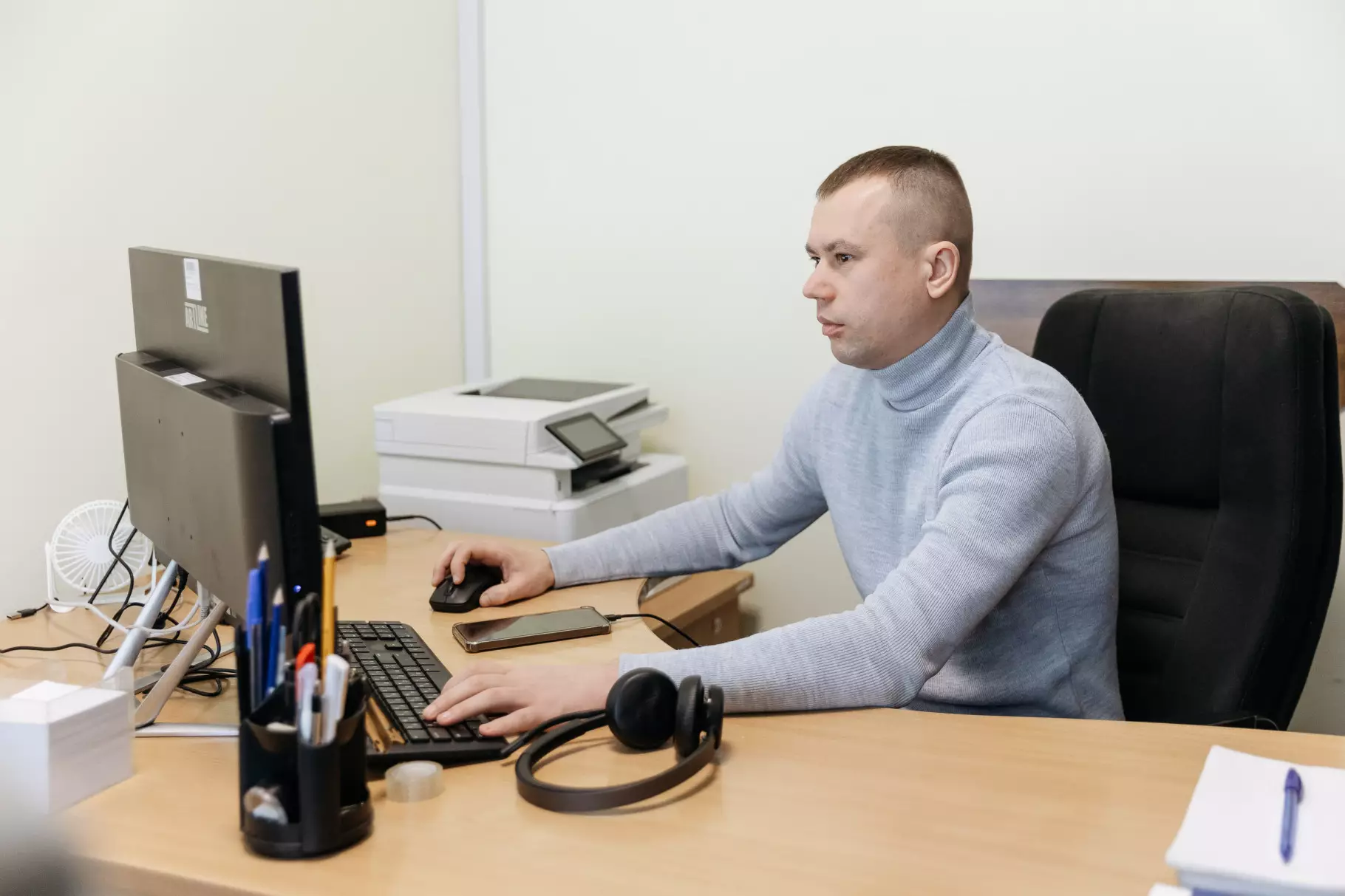 Оператор контакт-центру МВС працює за комп'ютером, навушники лежать на столі поруч з телефоном