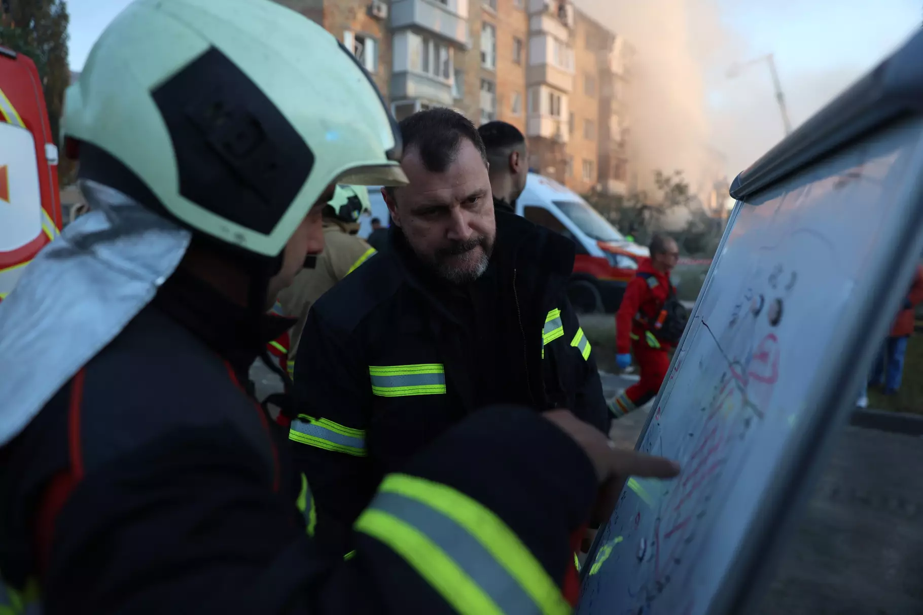 Рятувальники обговорюють план дій біля пошкодженої будівлі під час терористичних атак в Україні