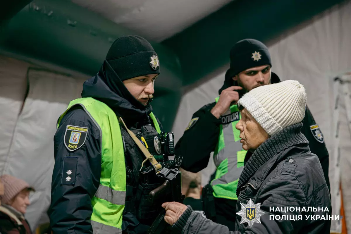 Поліцейські Національної поліції України спілкуються з жінкою в зимовому одязі в наметі
