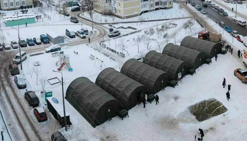 Великі намети обігріву встановлені у дворі багатоповерхівок у засніженому Києві, люди поруч