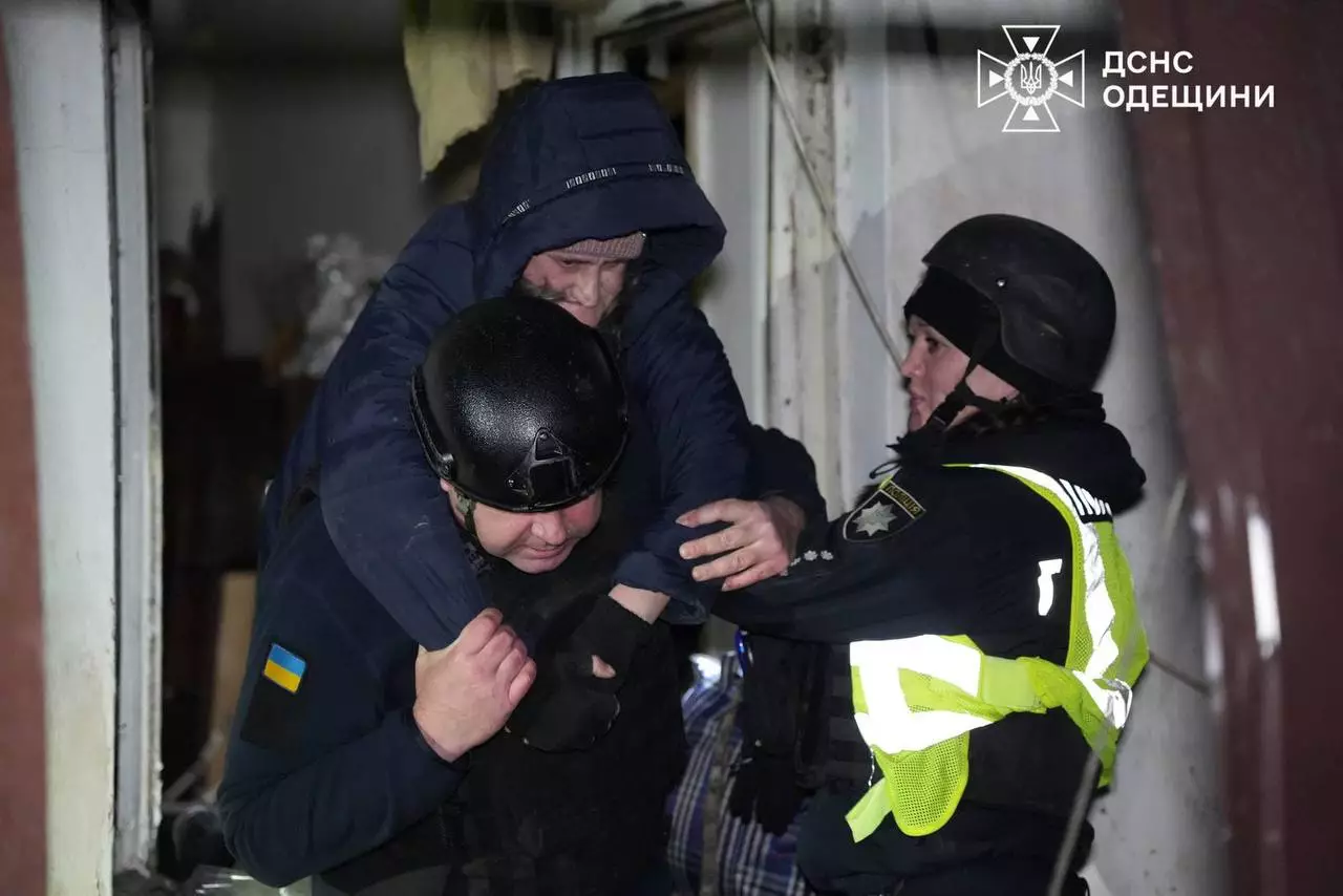 Рятувальники допомагають постраждалому під час нічної атаки дронами в Одесі, евакуація зруйнованого будинку
