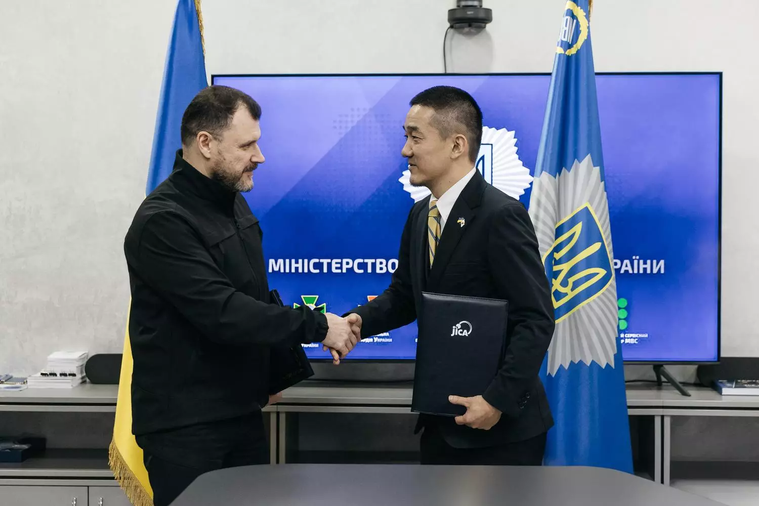 Міністр України та представник JICA підписують угоду на тлі прапорів та логотипу Міністерства