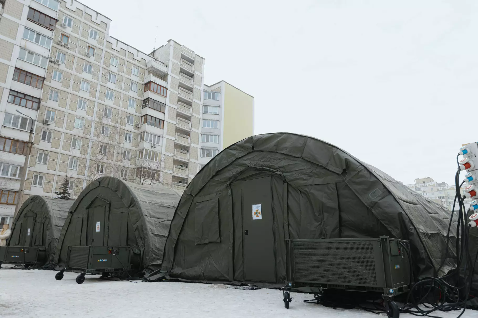 Наметове містечко ДСНС на Троєщині для обігріву мешканців після обстрілу, зима, багатоповерхівки на фоні