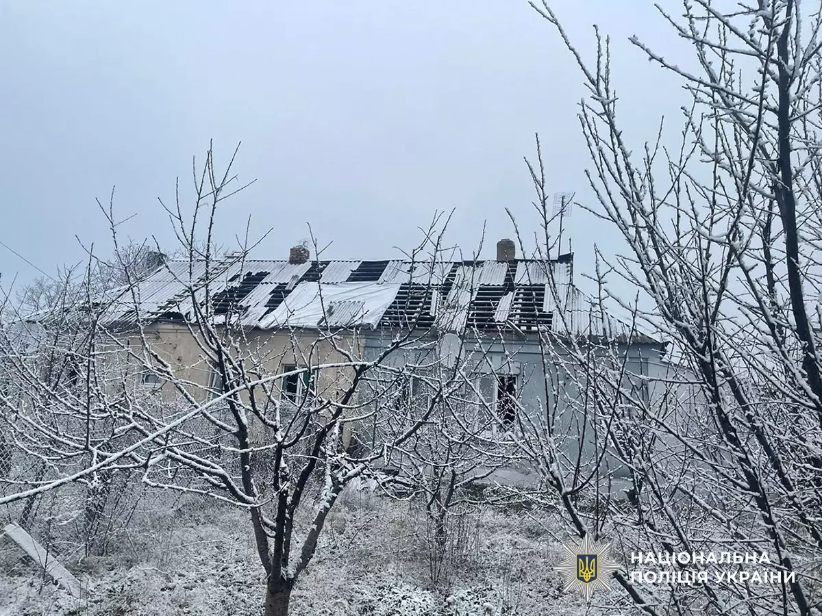 Зруйнований будинок у зимовому пейзажі після обстрілів, пошкоджений дах, засніжені дерева навколо