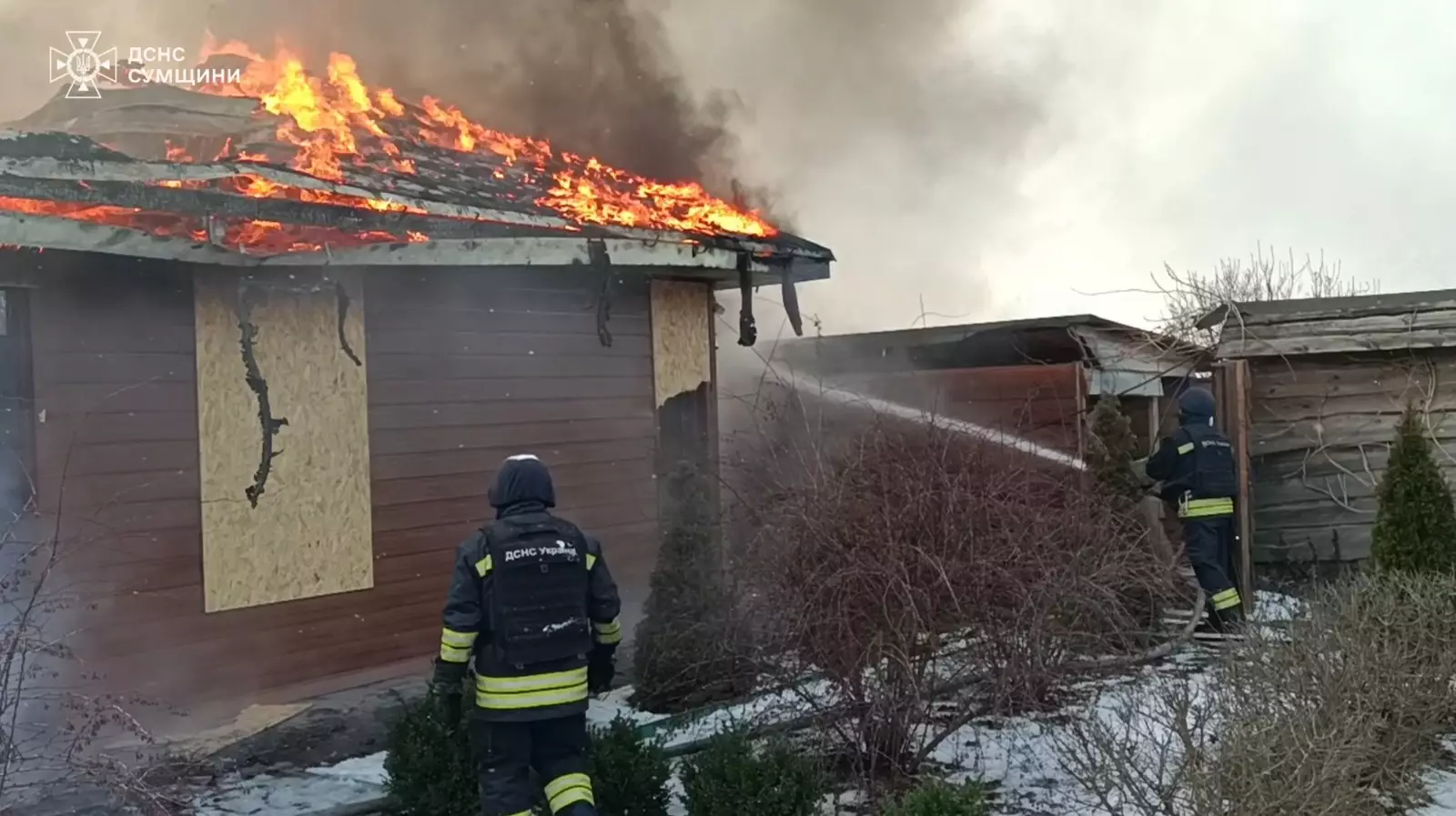 Пожежники гасять полум'я на даху будинку після обстрілу, дим піднімається в небо