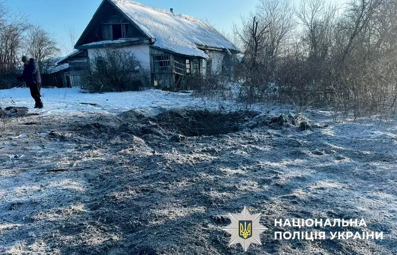 Зруйнована будівля та вирва від обстрілу на засніженій ділянці в прифронтовій зоні України