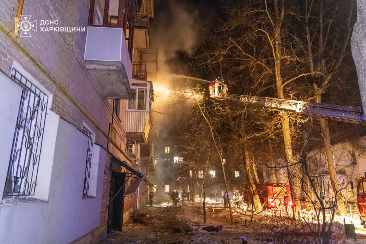 Рятувальники на пожежній драбині гасять вогонь у багатоповерхівці після нічного обстрілу в Харкові