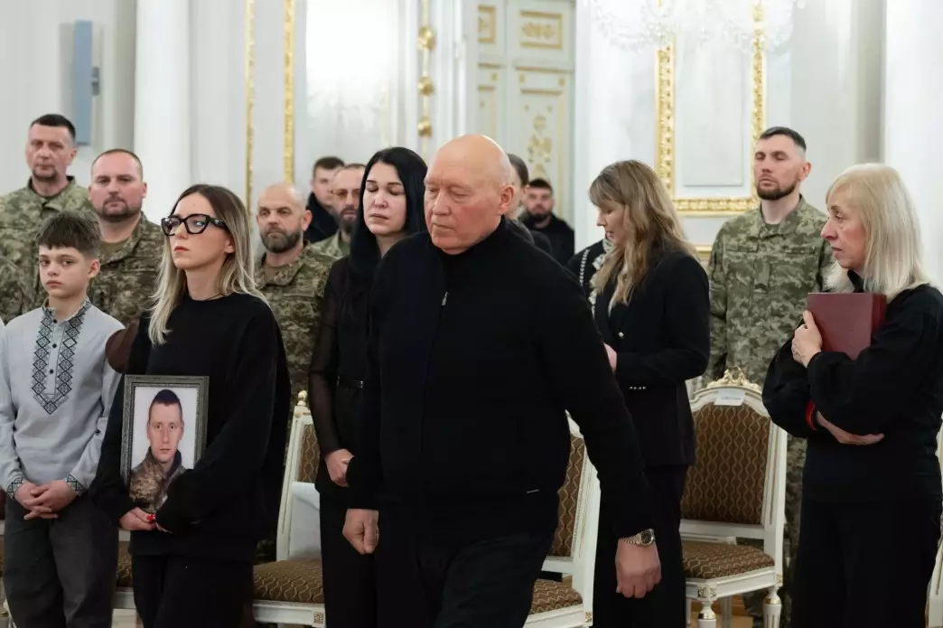 Люди в залі під час церемонії нагородження, тримають портрети загиблих героїв України