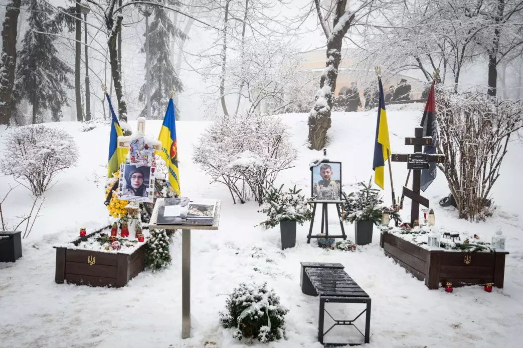 Засніжений меморіал Героїв Крут з українськими прапорами та портретами загиблих захисників