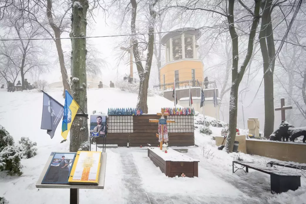 Аскольдова могила в снігу з пам'ятним хрестом Героям Крут, квітами та українським прапором