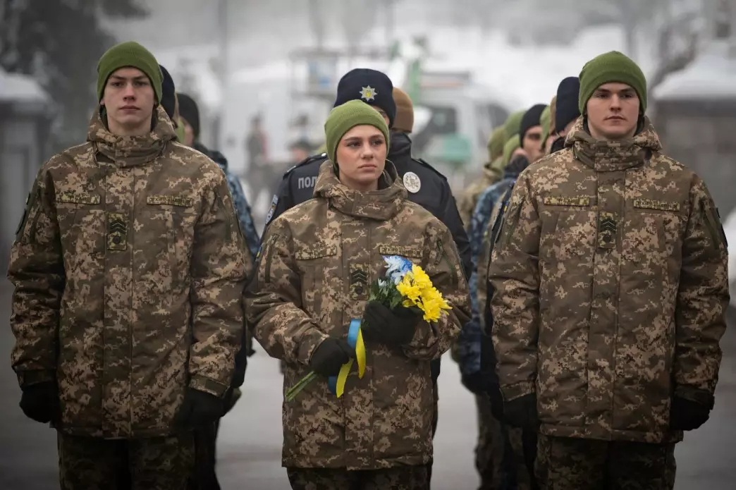 Українські військові в камуфляжі з квітами в руках під час вшанування пам'яті Героїв Крут у Києві