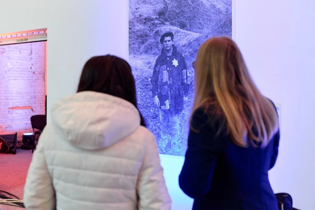 Дві жінки дивляться на історичну фотографію жертви Голокосту на конференції в Києві