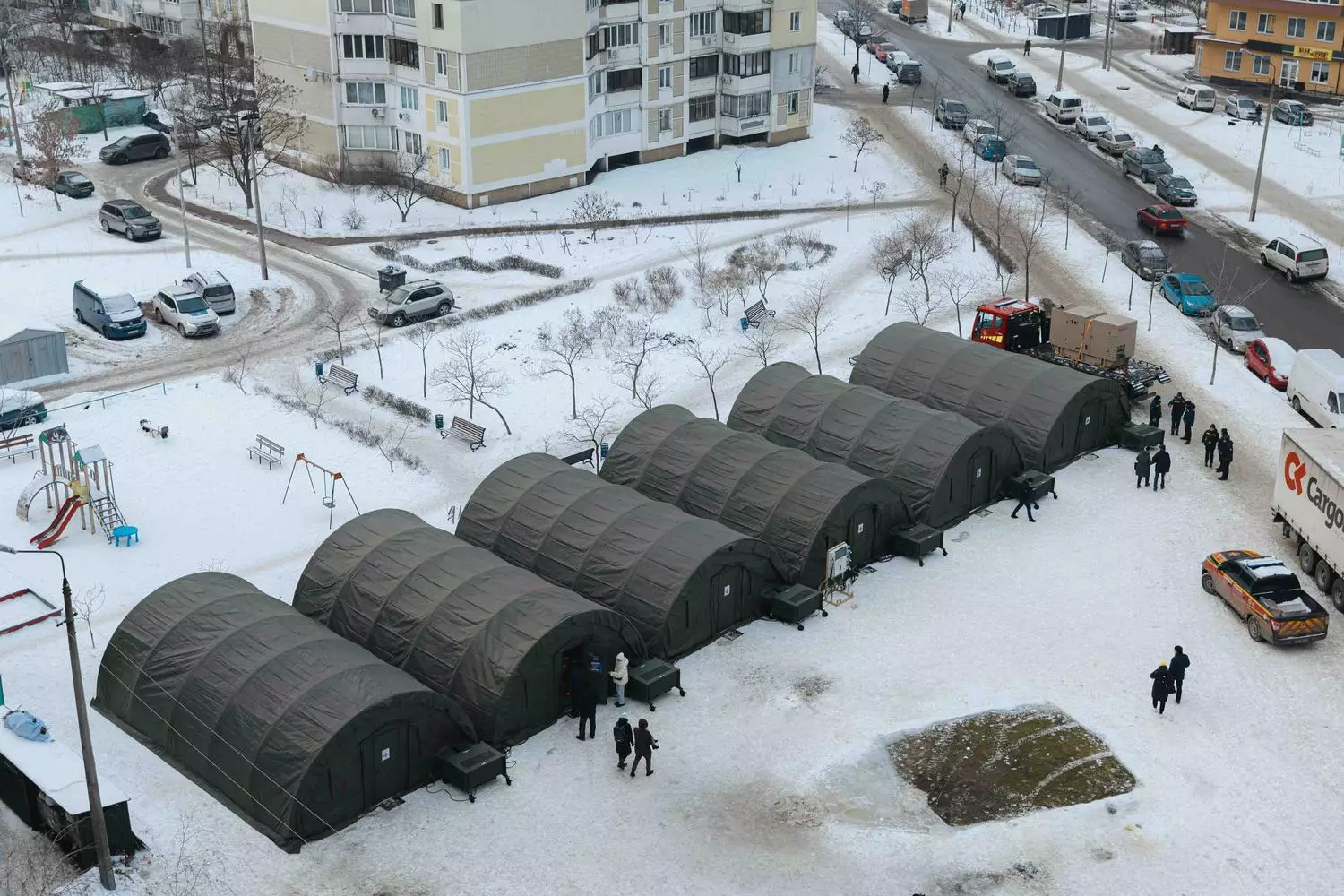 На зображенні кілька наметів ДСНС для обігріву людей у засніженому міському районі Києва