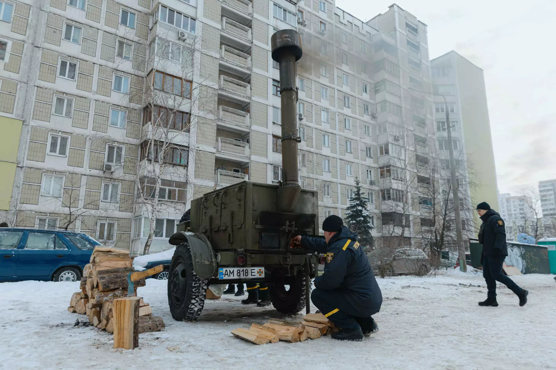 Рятувальники ДСНС біля мобільної печі в пункті обігріву на тлі багатоповерхівок у зимовому Києві