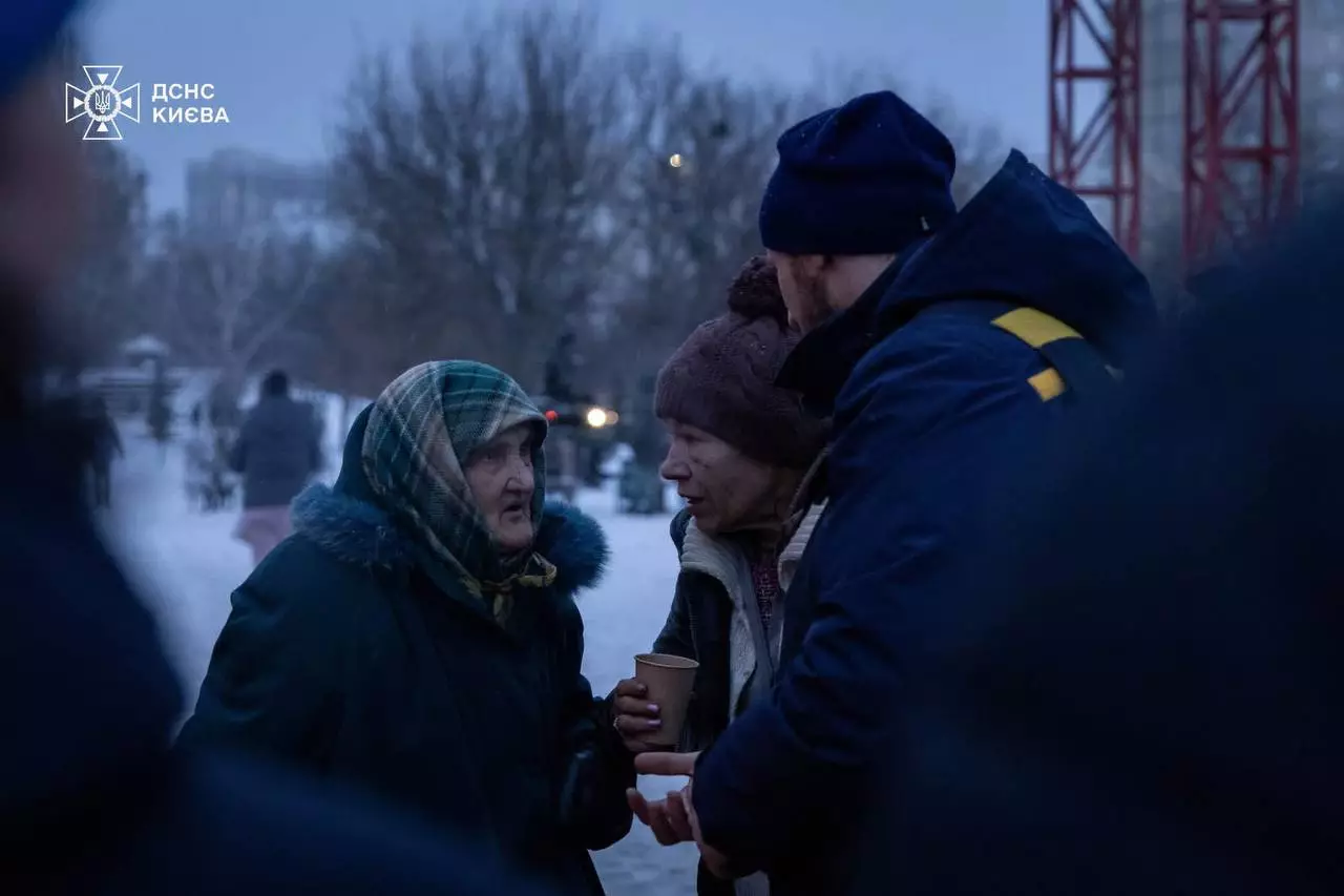 Люди спілкуються біля мобільного пункту обігріву ДСНС у зимовий день, отримуючи гарячі напої