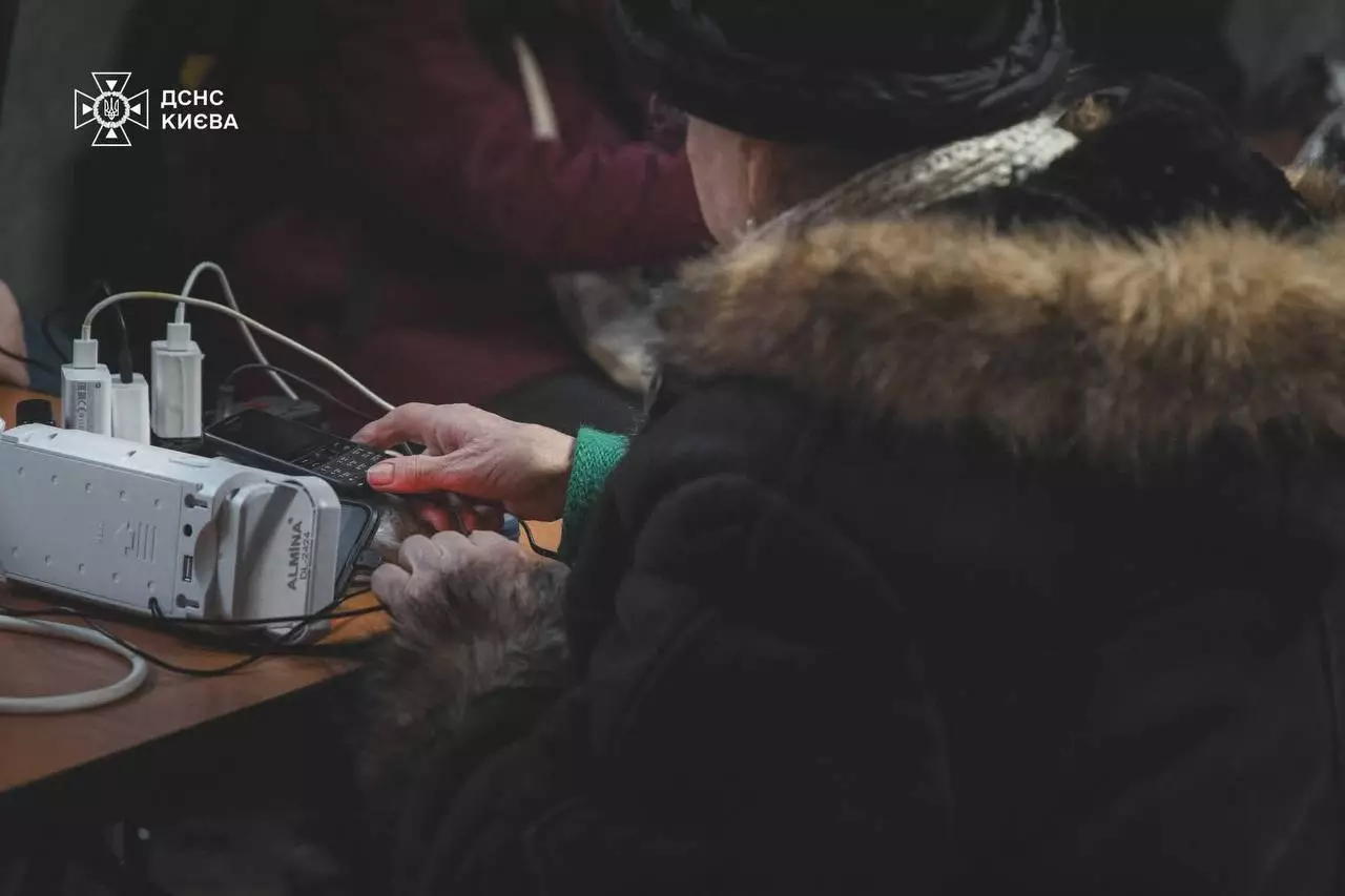 Людина заряджає пристрій у пункті незламності, забезпеченому генераторами та стабільним зв’язком