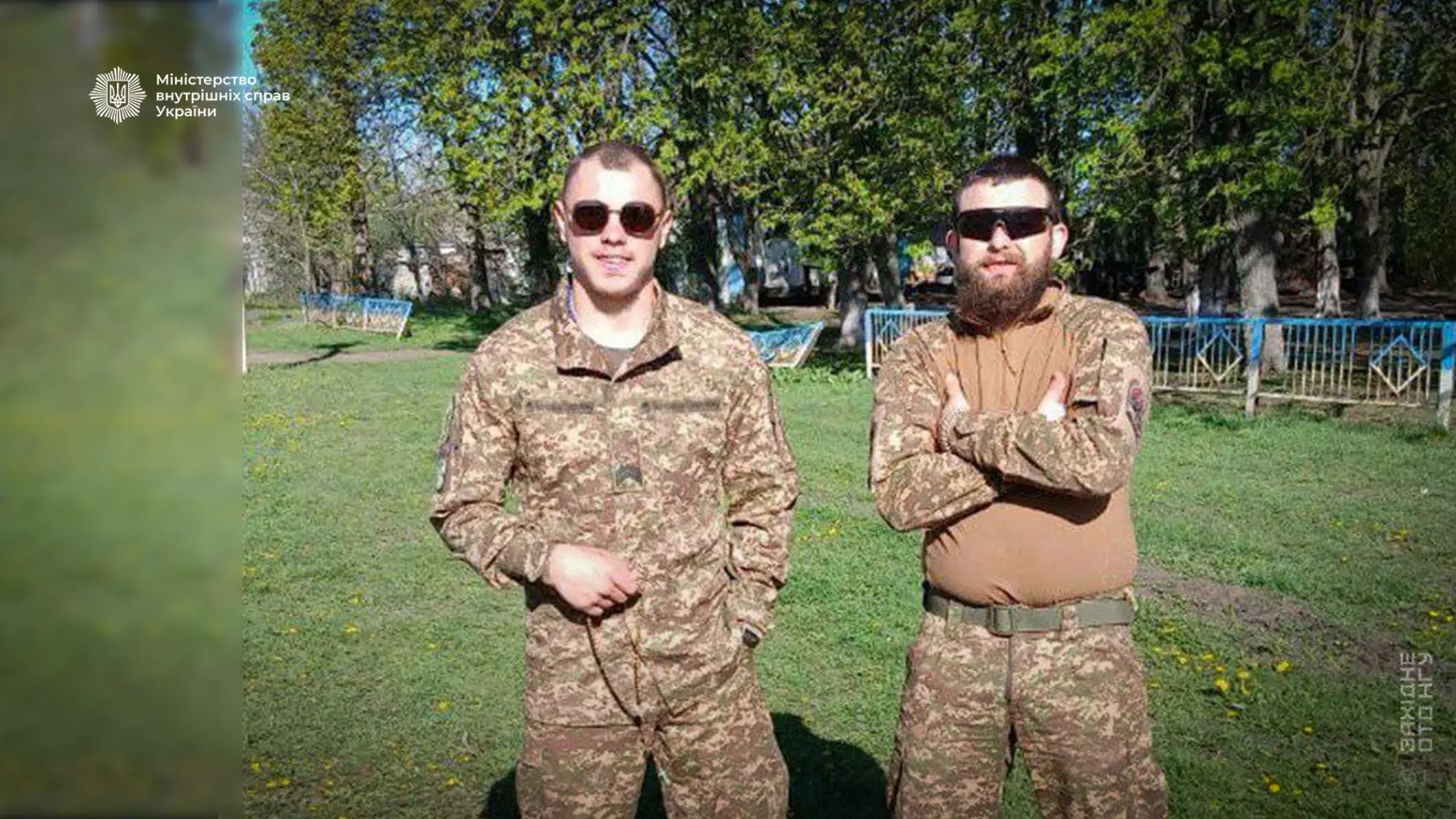 Двоє гвардійців у камуфляжі стоять на траві, позаду дерева, символізуючи командний дух та стійкість
