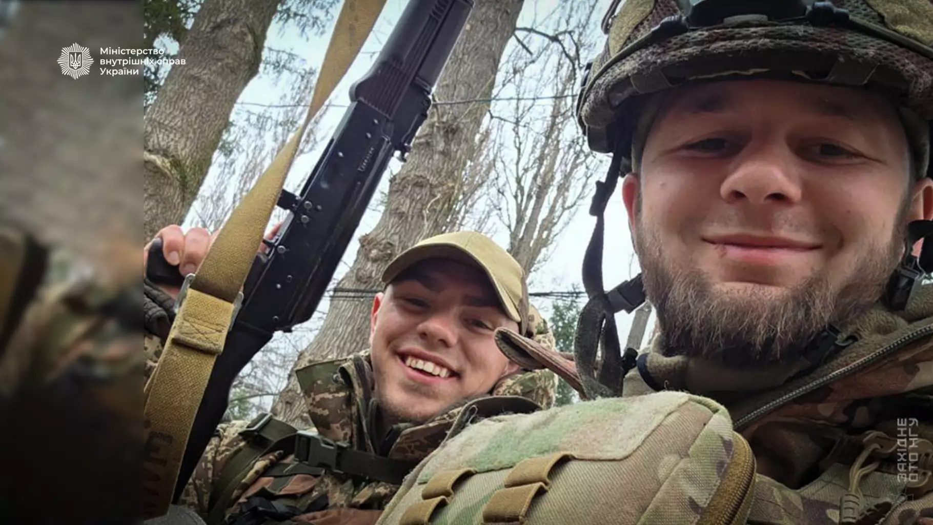 Двоє українських гвардійців у військовій формі з автоматами, усміхаються на тлі дерев