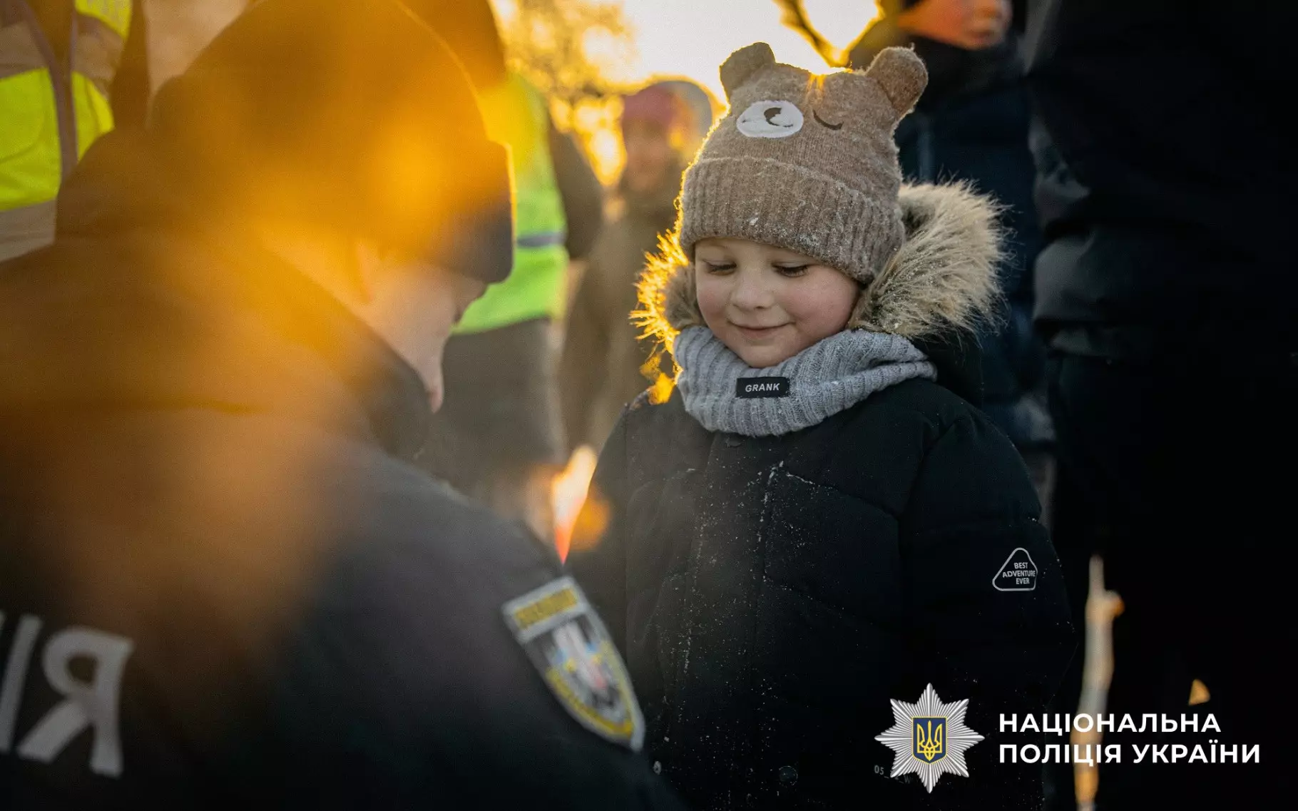 Дитина в зимовому одязі отримує світловідбивальний елемент від поліцейського на вулиці