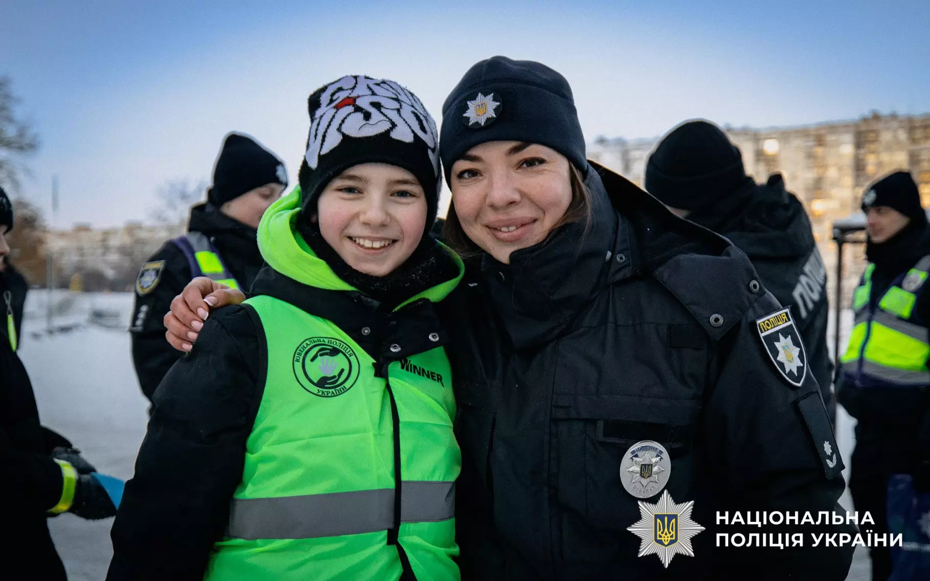 Ювенальний поліцейський обіймає дитину в світловідбивальному жилеті на зимовій прогулянці