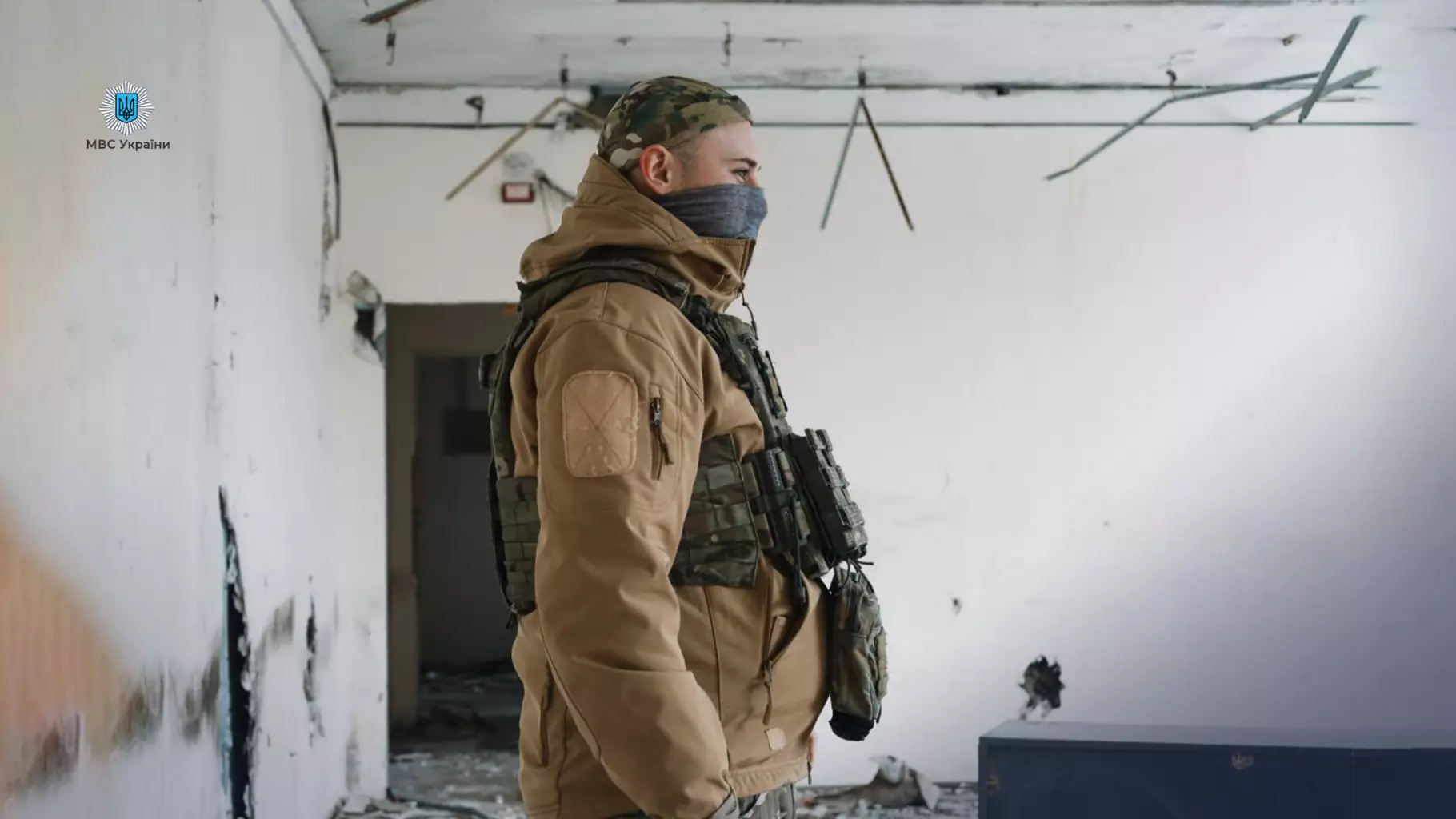 Прикордонник у камуфляжі стоїть у зруйнованій будівлі на лівобережжі Херсонщини, готовий до дій