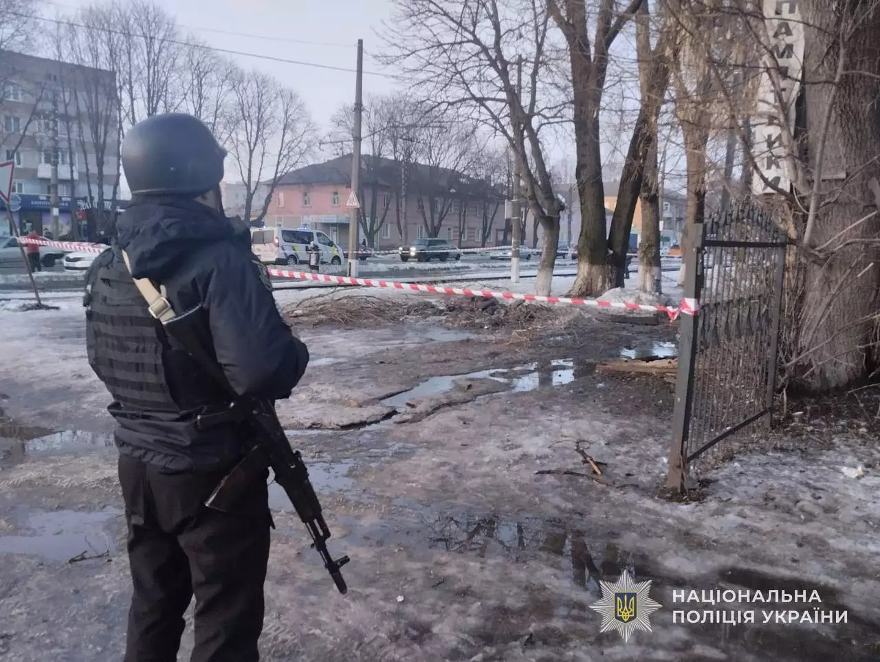 Поліцейський з автоматом на місці обстрілу, огороджене стрічкою, пошкоджена територія в Україні