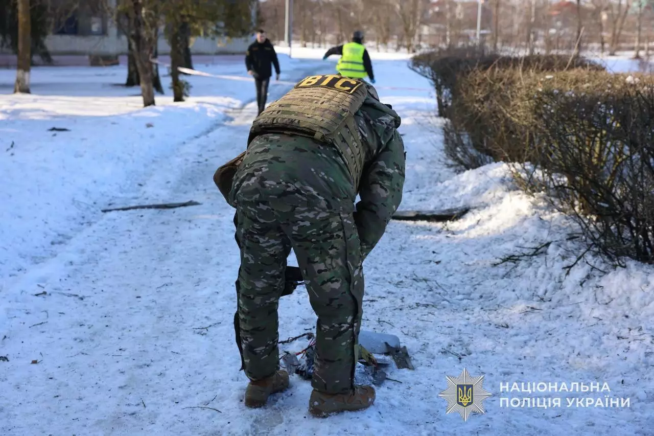 Поліцейський у камуфляжі оглядає уламки на засніженій дорозі після обстрілу в Україні
