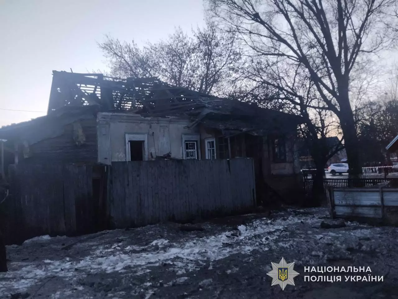 Зруйнований будинок після обстрілу, пошкоджений дах і фасад, навколо сніг та уламки