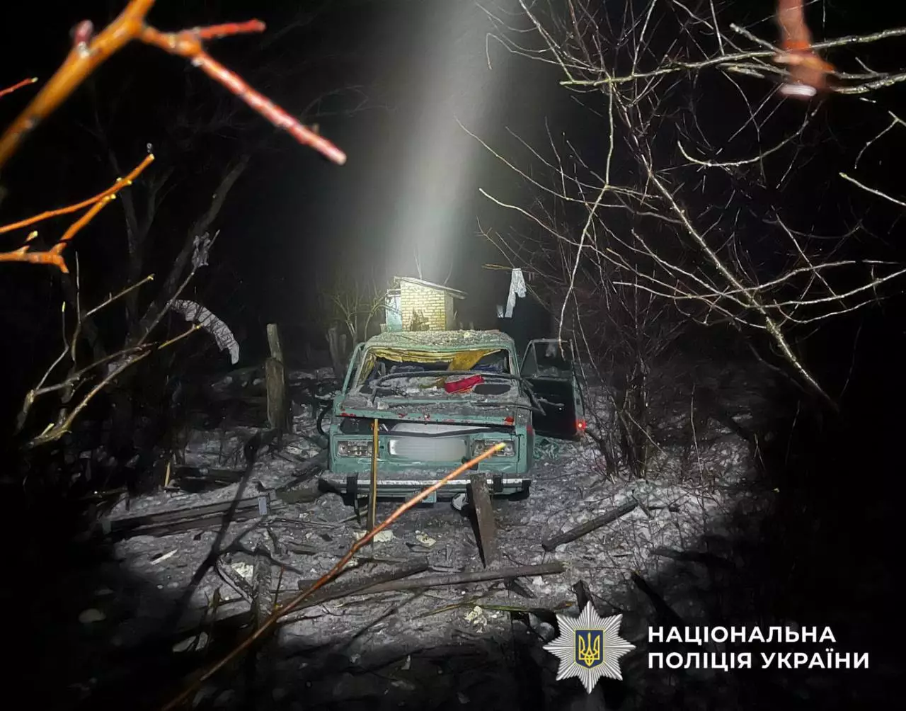 Автомобіль пошкоджений внаслідок обстрілу, навколо уламки та гілки, нічна зйомка на місці події