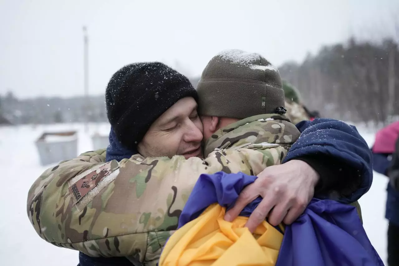 Двоє військових обіймаються на тлі зимового пейзажу, один тримає український прапор