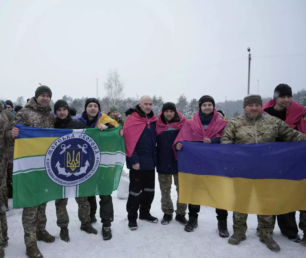Українські військові з прапорами на снігу, радісно зустрічають повернення додому
