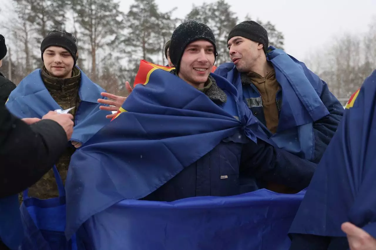 Троє військових, загорнуті в сині прапори, радісно зустрічають повернення додому