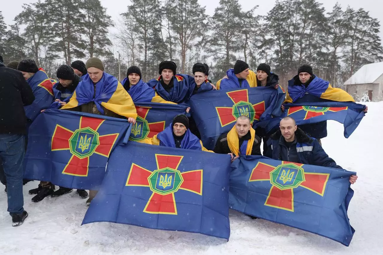 Українські військові з прапорами нацгвардії повертаються додому після обміну полоненими на тлі зимового пейзажу