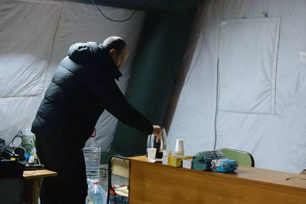 Чоловік у теплому одязі готує напої в наметі обігріву, розташованому в пункті незламності