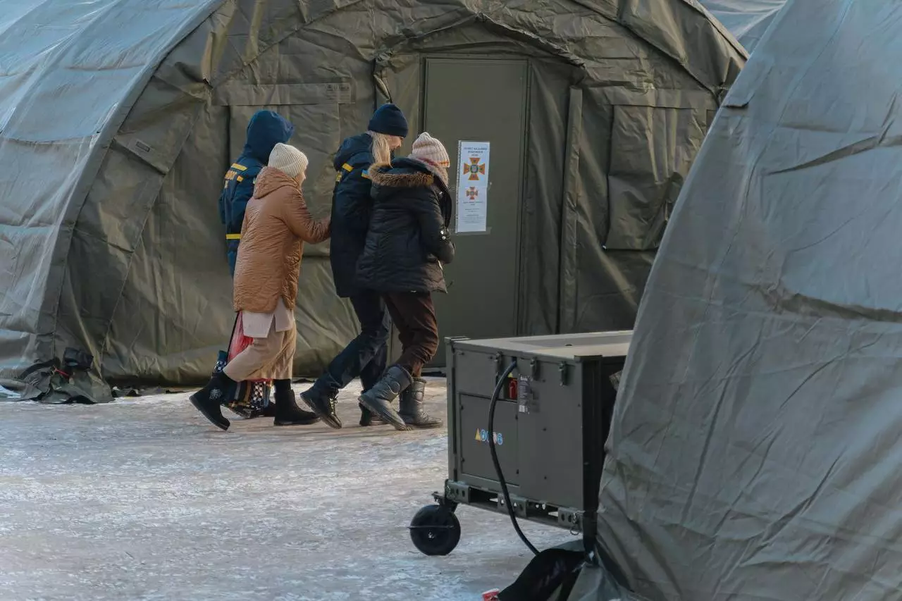 Люди заходять у великий наметовий пункт обігріву на засніженій території