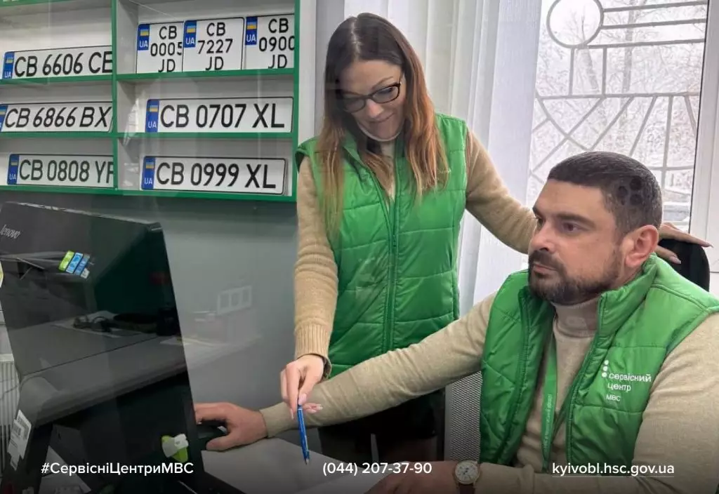Чоловік і жінка в уніформі сервісного центру МВС працюють за комп'ютером, обговорюючи документи