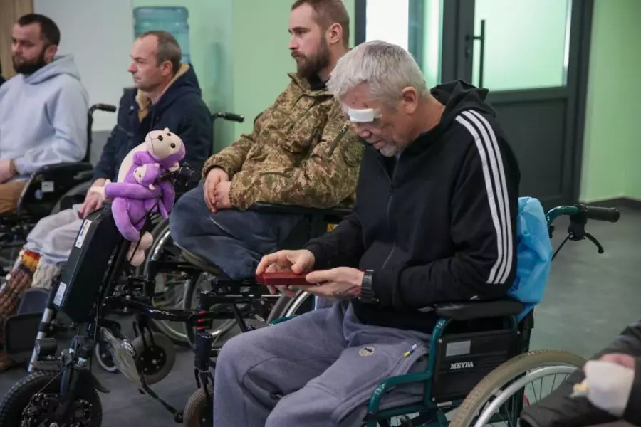 Поранені військовослужбовці НГУ в інвалідних візках, один з них тримає нагороду, інший з іграшкою
