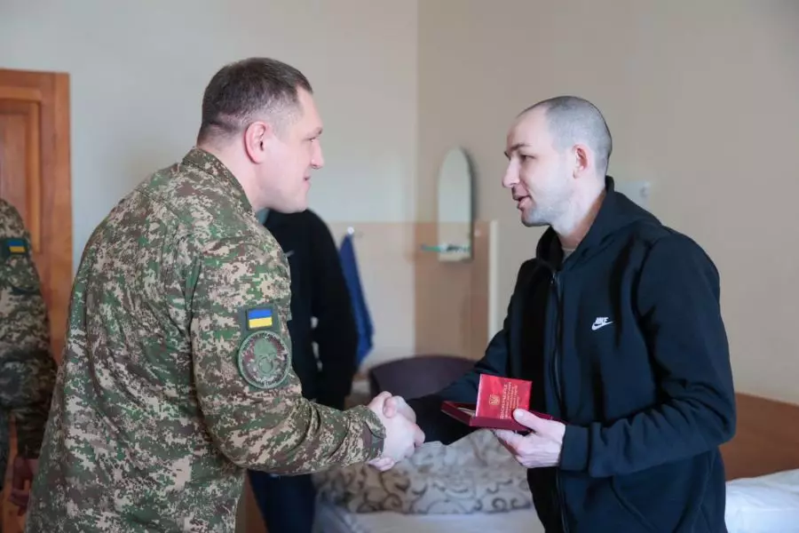 Командувач НГУ тисне руку пораненому нацгвардійцю в лікарняній палаті, вручаючи нагороду