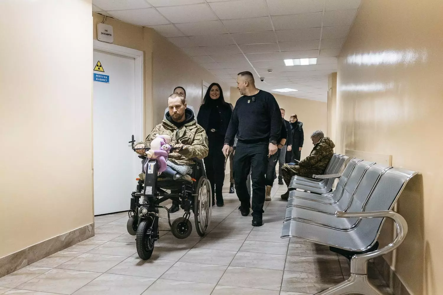 Поранений ветеран у військовій формі на електроколясці в коридорі госпіталю з медичним персоналом