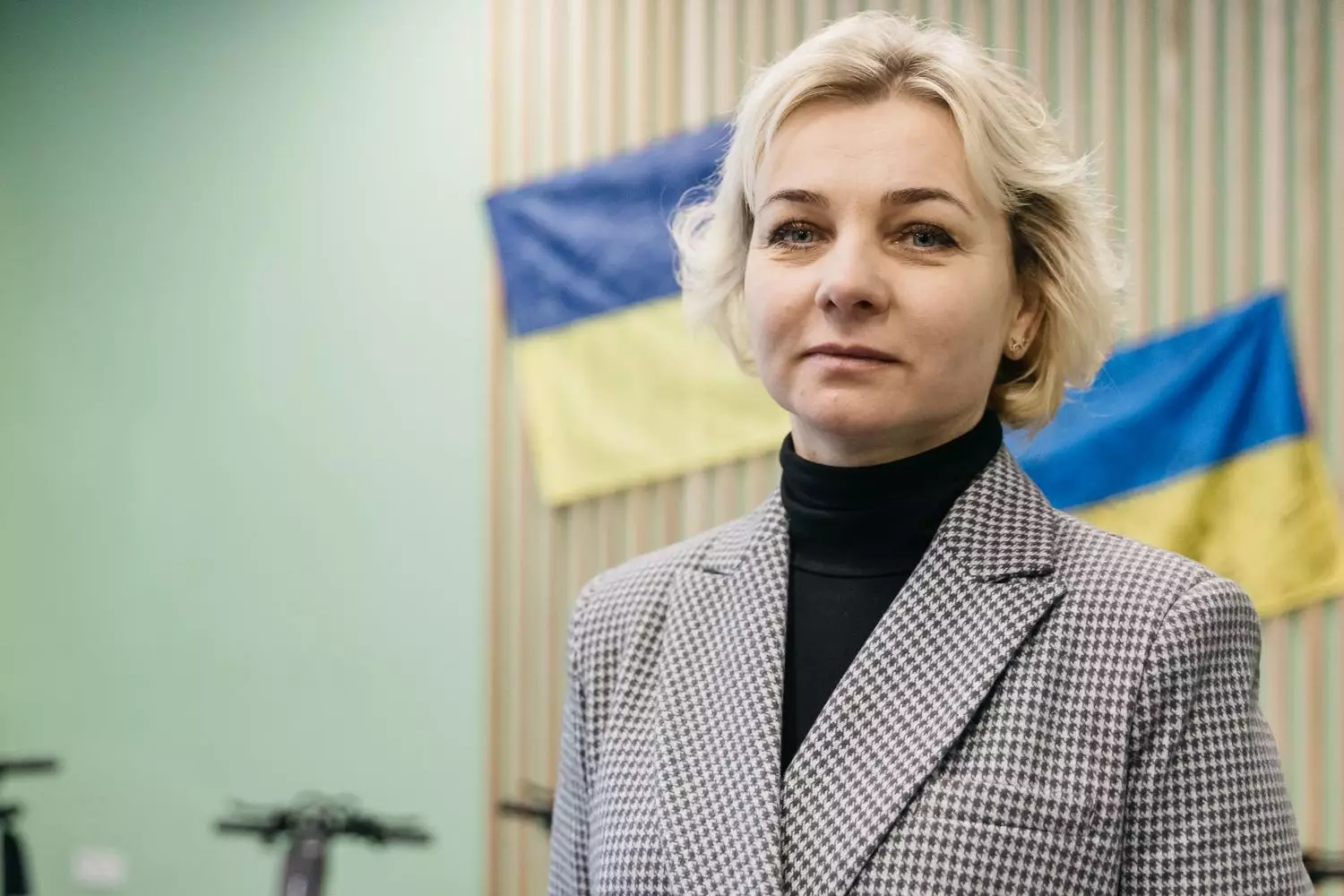 Жінка в діловому костюмі на фоні прапорів України, презентація медичного обладнання для реабілітації