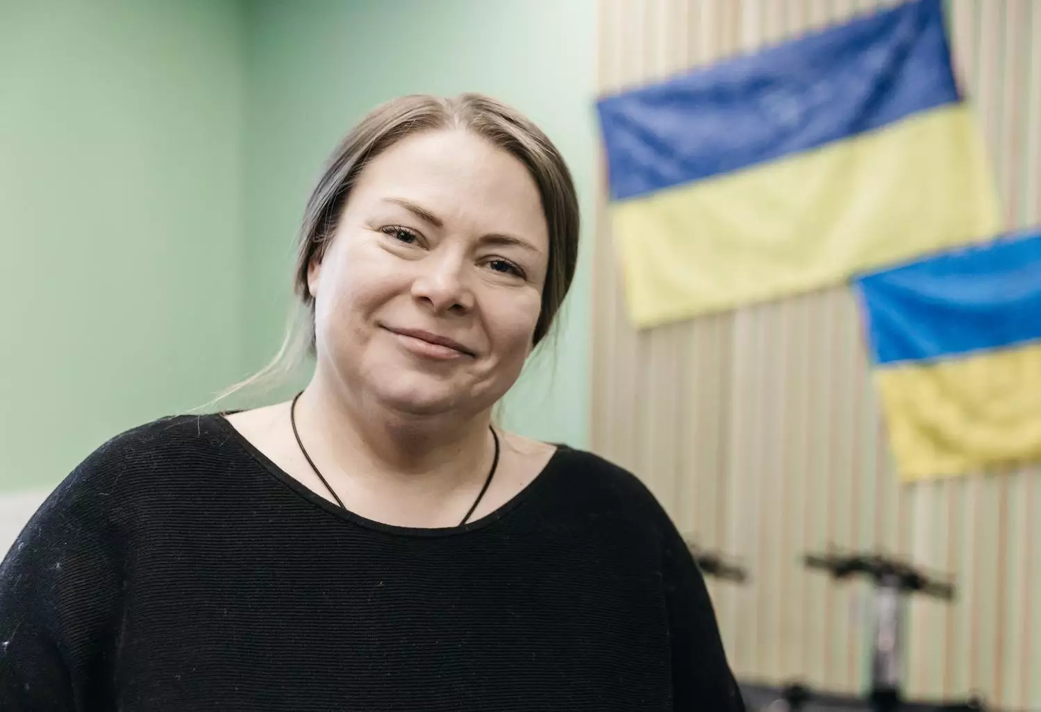 Жінка усміхається на фоні українського прапора в приміщенні медичного центру