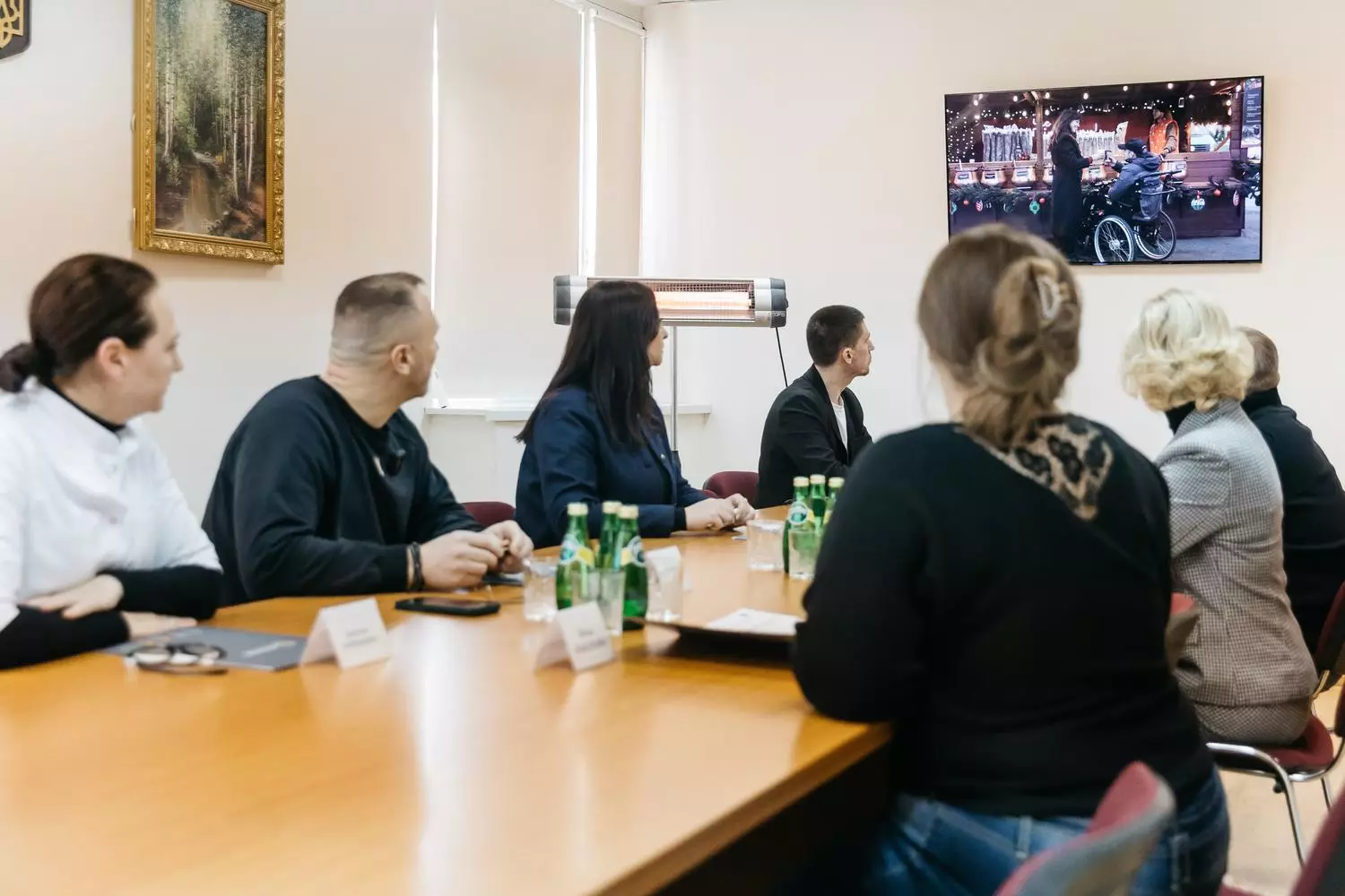 Люди на зустрічі в офісі дивляться презентацію на екрані про електроприводи для крісел колісних