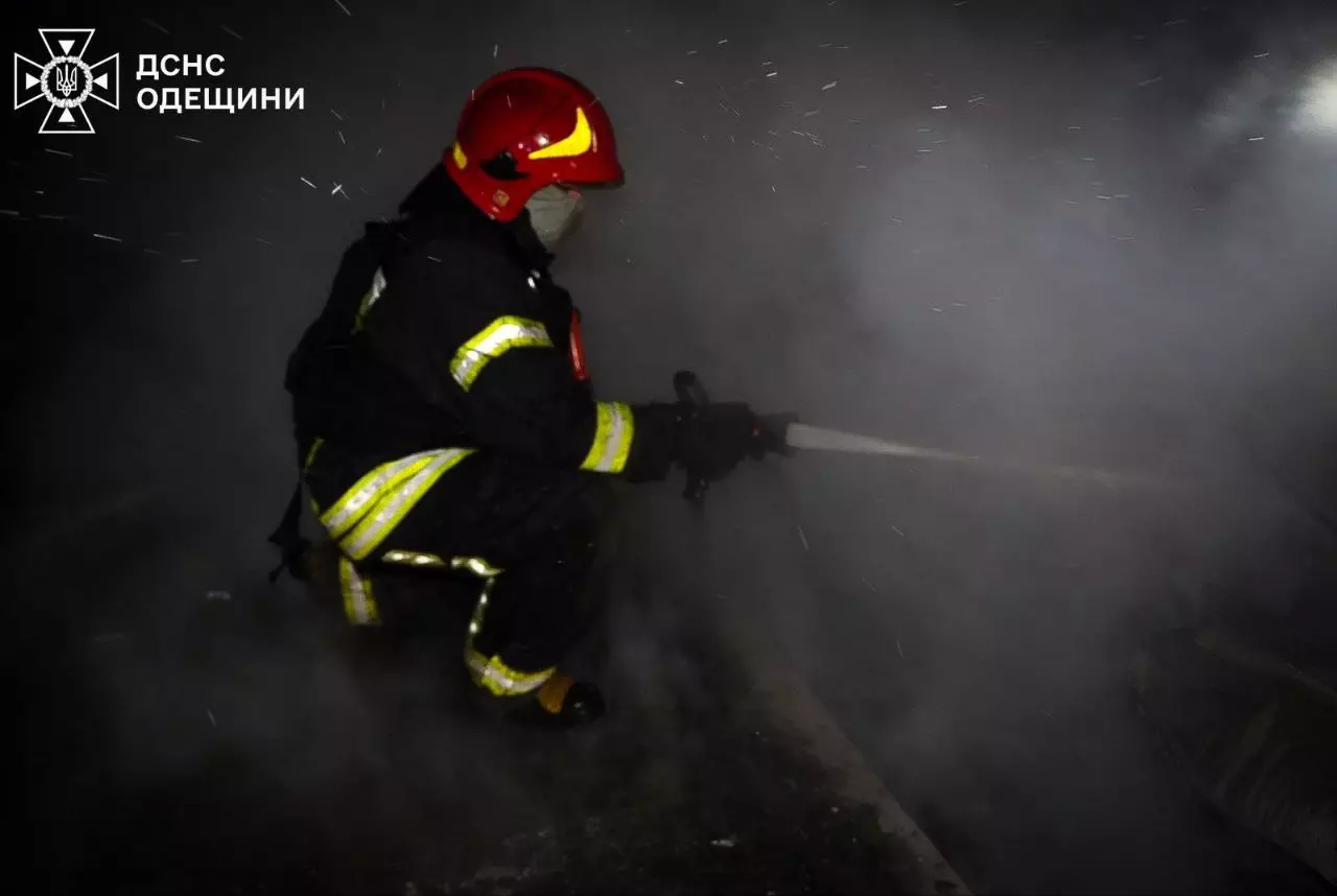 Рятувальник у захисному одязі гасить пожежу після обстрілу в густому диму