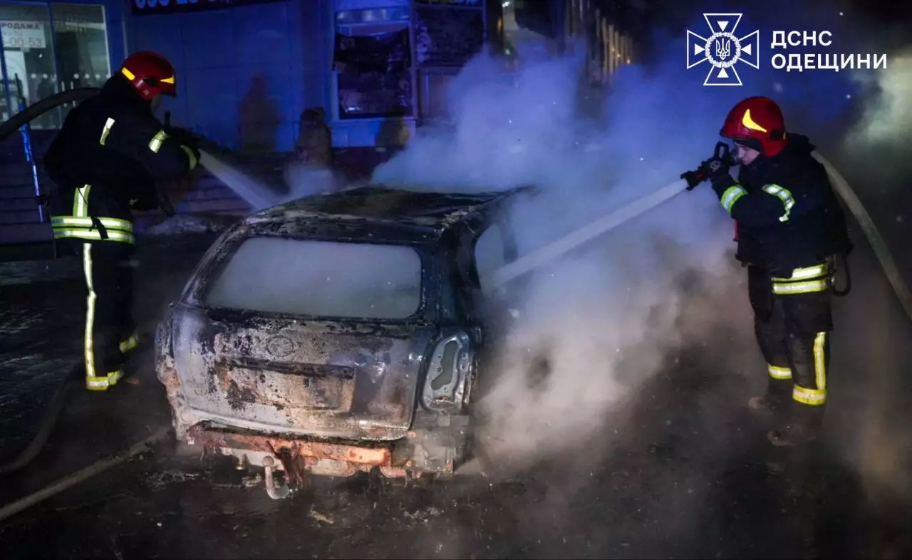 Пожежники гасять палаючий автомобіль після обстрілу вночі, густий дим піднімається вгору