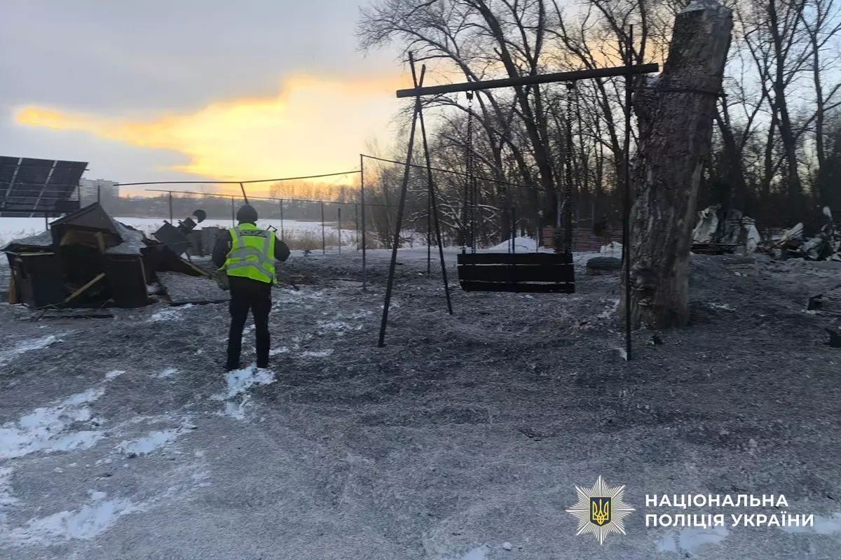 Поліцейський оглядає зруйновану територію після обстрілу, навколо сніг та обгорілі залишки будівель